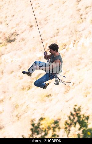 Mann mit Sicherheitsgurt, der den Felsberg klettert Stockfoto