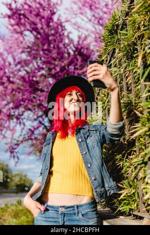 Frau mit der Hand in der Tasche nimmt Selfie über das Smartphone an sonnigen Tag Stockfoto