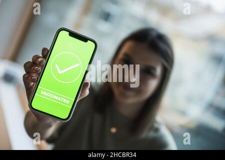 Frau, die auf dem Handy-Bildschirm ein Häkchen für die Impfung zeigt Stockfoto