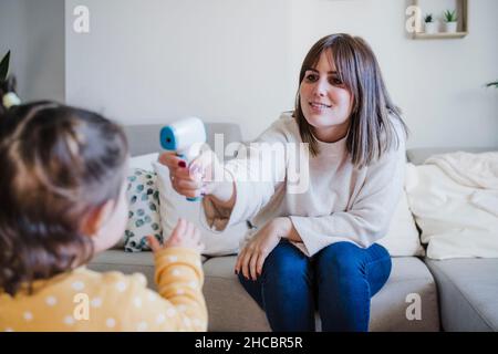 Mutter, die die Temperatur des kleinen Mädchens zu Hause misst Stockfoto