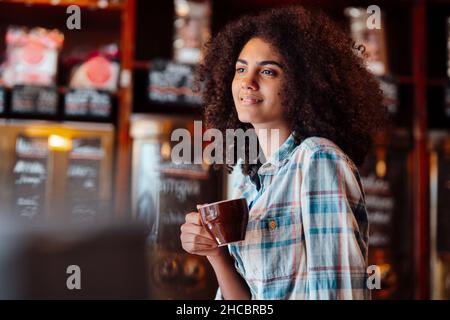 Der aufmerksame Besitzer hält eine Kaffeetasse in der Rösterei Stockfoto