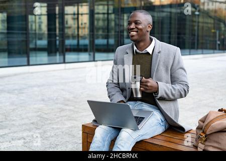 Der Mann mit dem Laptop sitzt auf der Bank Stockfoto