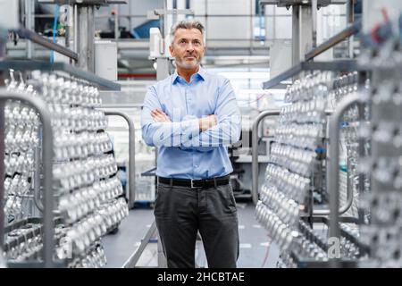 Nachdenklicher Geschäftsmann mit gekreuzten Armen in der Elektroindustrie Stockfoto