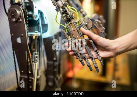 Techniker beim Händeschütteln mit Roboterarm in der Werkstatt Stockfoto