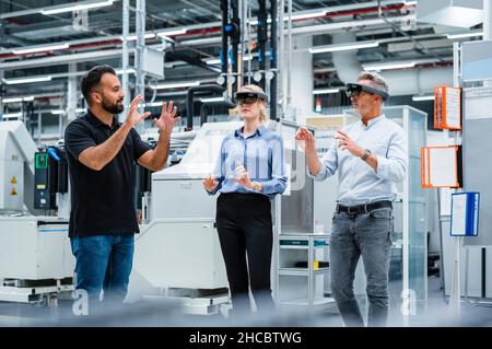 Ingenieur diskutiert mit Kollegen, die intelligente Brillen in der Industrie verwenden Stockfoto