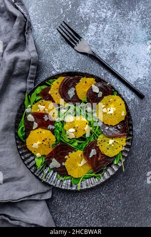 Studioaufnahme eines vegetarischen Carpaccitellers mit Orangen- und Rote Beete-Scheiben, Rucola, Parmesan und schwarzen Sesam Stockfoto