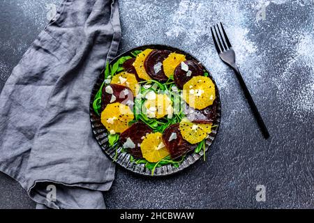 Studioaufnahme eines Carpacio-Tellers mit Orangen- und Rote Beete-Scheiben, Rucola, Parmesan und schwarzen Sesam Stockfoto