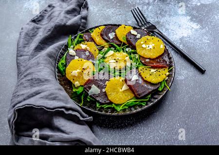 Studioaufnahme eines vegetarischen Carpaccitellers mit Orangen- und Rote Beete-Scheiben, Rucola, Parmesan und schwarzen Sesam Stockfoto