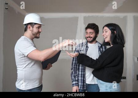 Das junge Paar erhält die Schlüssel für ihre neue Wohnung im Bau. Stockfoto