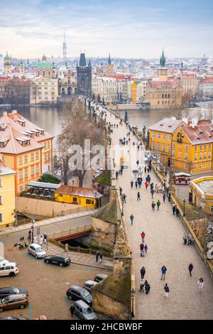 Die Menschen laufen auf der Karlsbrücke, deren Dächer von Schnee bedeckt sind, Prag im Winter Stockfoto