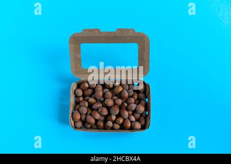 Box mit Haselnüssen über Stein Tisch, einem blauen Hintergrund Flatlay Stockfoto