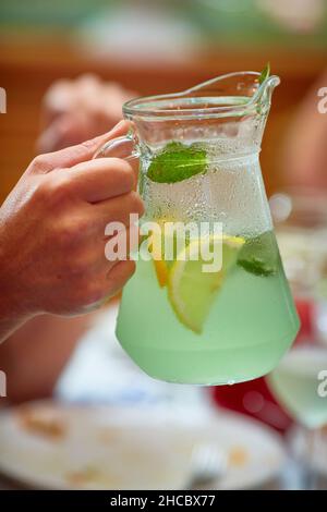 Die Hand des Mannes hält einen Krug mit grüner Limonade, ein kühles erfrischendes Sommergetränk Stockfoto