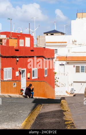 Ein Einheimischer, der eine Zigarette raucht, sitzt vor seinem Haus in der Straße von Pozo Izquierdo, Kanarische Inseln, Spanien Stockfoto