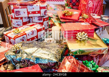 Stapel von Weihnachtsgeschenken, sorgfältig in festliches Papier eingewickelt und mit Schleifen und Bändern verziert. Stockfoto