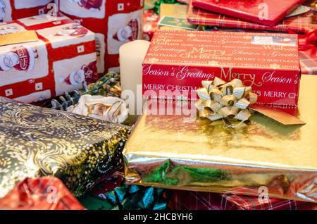 Stapel von Weihnachtsgeschenken, sorgfältig in festliches Papier eingewickelt und mit Schleifen und Bändern verziert. Stockfoto