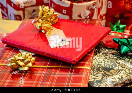 Stapel von Weihnachtsgeschenken, sorgfältig in festliches Papier eingewickelt und mit Schleifen und Bändern verziert. Stockfoto