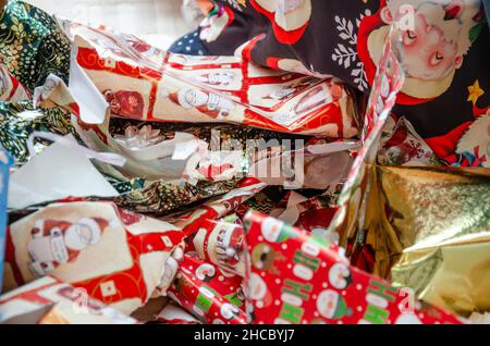 Stapel von weggeworfenen Weihnachten Geschenkpapier links auf dem Boden nach präsentiert geöffnet worden sind. Stockfoto