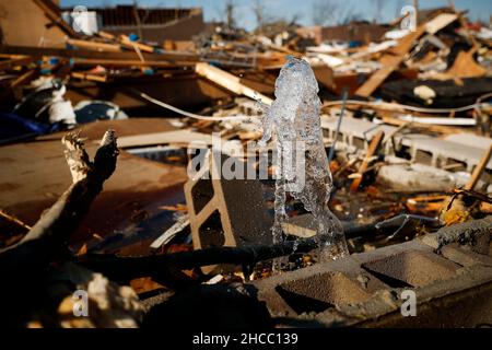 Dawson Springs, USA. 14th Dez 2021. Eine gebrochene Wasserlinie spuckt Wasser aus den Trümmern eines Hauses in der North 6th Street in Mayfield, Kentucky, Dienstag, 14. Dezember 2021. (Foto: Alex Blitz/Lexington Herald-Leader/TNS/Sipa USA) Quelle: SIPA USA/Alamy Live News Stockfoto