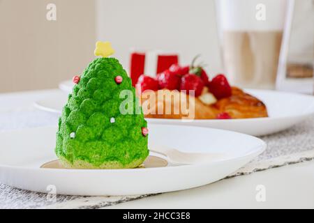 Weihnachtsbaum-Kuchen mit anderen Desserts im Hintergrund nicht im Fokus Stockfoto