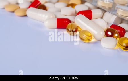 Verschiedene Arten von Pillen, Tabletten und Kapseln auf hellblauem Hintergrund mit Reflexion Nahaufnahme Stockfoto