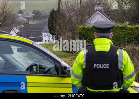 PSNI an der geschlossenen Radergan Road mit Blick auf Kellys Inn in der Omagh Road in Garvaghy, nachdem am Montag um etwa 1,50am Uhr drei Männer im Omagh Road-Gebiet getötet wurden und ein Auto und einen Lastwagen verwickelt waren. Bilddatum: Montag, 27. Dezember 2021. Stockfoto