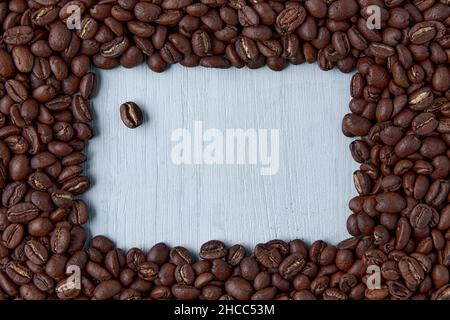 Designerrahmen aus Kaffeebohnen auf einem blauen Holztisch Stockfoto