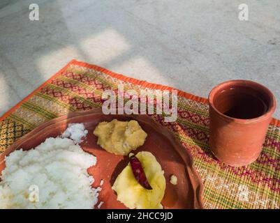 Traditionelle bengalische hausgemachte Thali oder Platte serviert auf Teller aus Ton. Gekochter Reis, Linsen und Kartoffeln. Authentische indische bengalische lokale Kultur Stockfoto