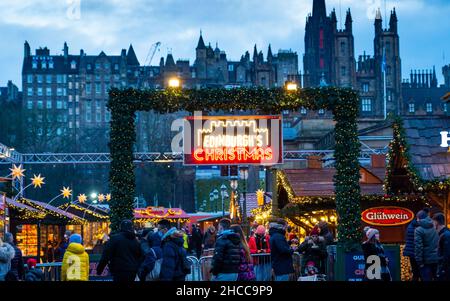 Edinburgh, Schottland, Großbritannien. 27th. Dezember 2021. Der Weihnachtsmarkt in Edinburgh wurde am zweiten Weihnachtsfeiertag mit neuen Regeln wiedereröffnet, um die Verbreitung der Omicron-Variante von Covid-19 zu verhindern, insbesondere wird nur ein Eingang verwendet, um die Anzahl zu heben. Besucher werden gebeten, vor dem Besuch einen seitlichen Durchflusstest durchzuführen. Tragen Sie eine Maske, halten Sie sich etwa 2m auseinander und folgen Sie den Schildern in den Gärten der East Princes Street. Iain Masterton/Alamy Live News. Stockfoto