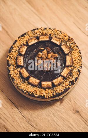 Draufsicht auf einen runden Schnapskochkochkuchen mit Nüssen-Krümel auf einem Holztisch Stockfoto