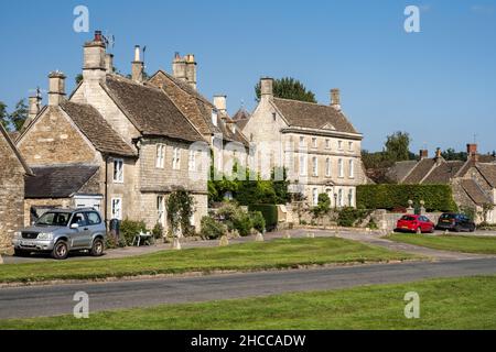 Traditionelle Steinhütten und Häuser sind rund um Biddestone Village Green in Englands Cotswold Hills angeordnet. Stockfoto