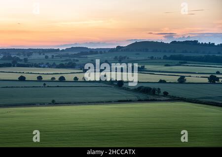 Die Sonne geht über dem langen Knoll-Hügel und dem Ackerland von Kilmington unter, wie man es vom White Sheet Hill in den West Wiltshire Downs aus sieht. Stockfoto