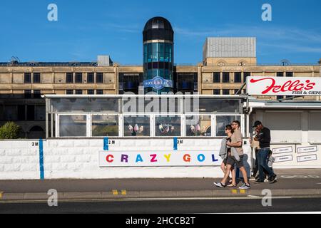 Touristen kommen an einer Crazy Golf-Attraktion an der Strandpromenade von Weston-Super-Mare in Somerset vorbei. Stockfoto