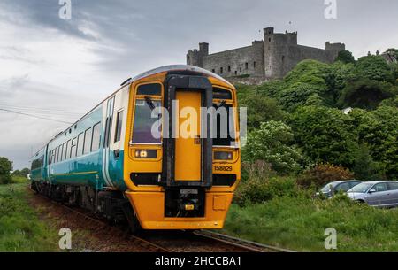 Harlech, Wales, Großbritannien - 11. Mai 2011: Ein Personenzug der Klasse 158 auf der eingleisigen Cambrian Coast Line-Bahn fährt am mittelalterlichen Schloss von Harlech vorbei Stockfoto