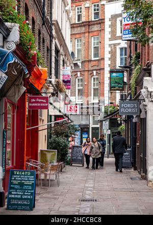 Fußgänger kommen am Red Lion Square im Zentrum Londons an Geschäften und Cafés vorbei. Stockfoto