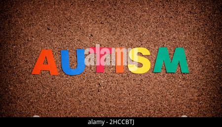 Autismus. Autismus-Spektrum-Störung. Autismus-Wort aus Karton. Hintergrund Korkbrett. Nahaufnahme. Stockfoto