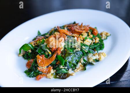 Gebratene Melinjo-Malindjoblätter mit Ei und knusprig getrockneten Garnelen, thailändisches Essen umrühren Stockfoto