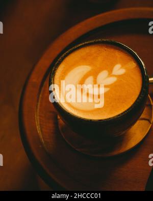 Nahaufnahme eines frischen heißen Cappuccinos mit Herzschaum auf einem Holztisch Stockfoto