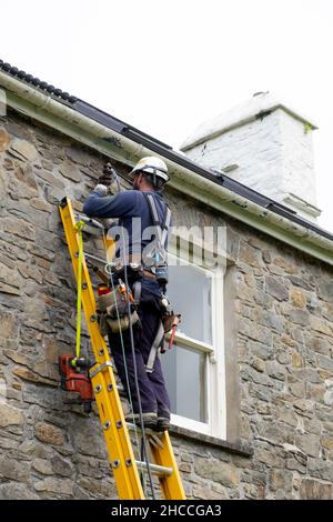 Stromarbeiter arbeitet beim Anschließen von Kabeln für die Stromversorgung auf einem ländlichen Grundstück Steinhaus in Wales Großbritannien 2021 KATHY DEWITT Stockfoto