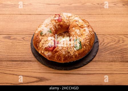 Roscón gefüllt mit Creme mit Mandeln, kandierten Früchten, Puderzucker und einem goldenen Tablett Stockfoto