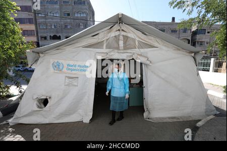 Gaza, Palästina. 27th Dez 2021. Palästinensischer Arzt steht vor einem Zelt für den COVID-19-Test in einer medizinischen Klinik im Al-Shati-Flüchtlingslager, das palästinensische Gesundheitsministerium im Gazastreifen hat den ersten Fall einer omicron-Variante im Gazastreifen angekündigt und sagte, dass diese Infektion von Israel in den Gazastreifen durch einen palästinensischen Arbeiter übertragen wurde, der in Israel arbeitete, Außerdem baten sie die Menschen, eine frühzeitige Untersuchung durchzuführen, indem sie Proben entnahmen und die erforderlichen Impfungen gegen die COVID-19-Pandemie erhielten. Kredit: SOPA Images Limited/Alamy Live Nachrichten Stockfoto