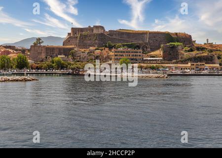 Kerkyra Stadtbild mit neuer Festung. Korfu Insel, Griechenland. Meeresbucht mit ruhigem türkisfarbenem Wasser, bunten alten Häusern, blauem Himmel mit weißen Wolken. Stockfoto