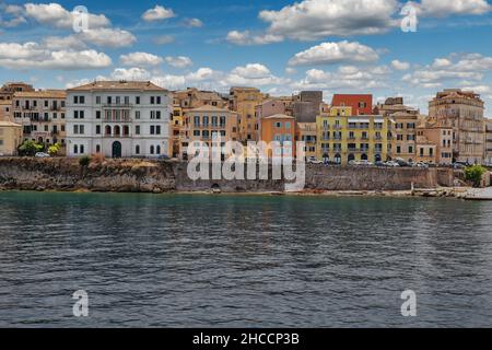 Stadtbild von Kerkyra. Korfu Insel, Griechenland. Meeresbucht mit ruhigem türkisfarbenem Wasser, bunten alten Häusern, blauem Himmel mit weißen Wolken. Stockfoto