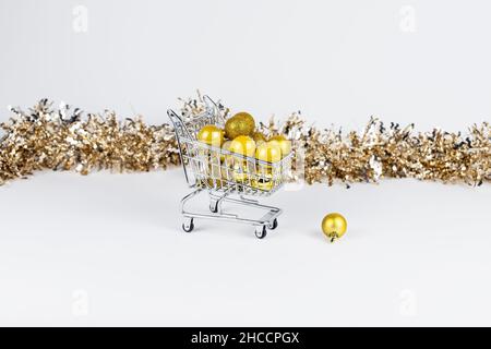Shopping Trolley voller Weihnachtskugeln und Lametta Komposition. Stockfoto