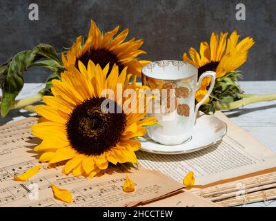 Sonnenblumen, Kaffeebecher und alte Bücher mit Musiknoten Stockfoto