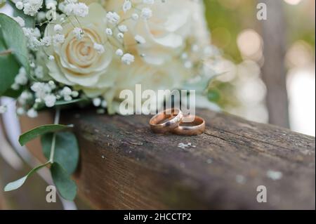 Hochzeitsstrauß mit frischen Blumen, ein Paar goldene Ringe aus der Nähe. Hochzeitsdetails Stockfoto