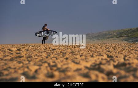 Landschaft eines großen Strandes mit nicht erkennbaren Surfern, die auf den Moment warten, um ins Meer zu kommen und Wellen zu fangen, währenddessen schauen sie sich Fotos auf Th an Stockfoto