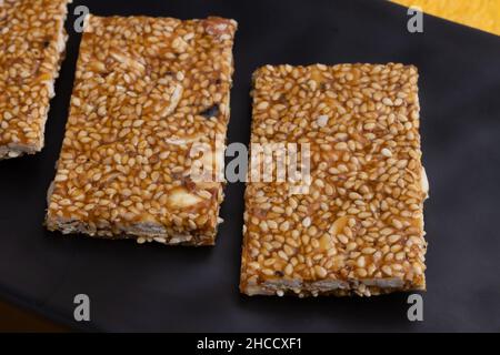 Süßigkeiten Mithai aus Indien isoliert auf gelbem Hintergrund für Makar Sankranti Lohri Gajak auch bekannt als Gur Gajjak Gazak Kachak Til Patti Stockfoto