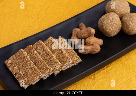 Süßigkeiten Mithai isoliert auf gelbem Hintergrund für Makar Sankranti Lohri Gajak auch bekannt als Gur Gajjak Gazak Kachak Til Patti Erdnüsse Mandeln Stockfoto