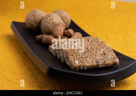 Indische traditionelle Süßigkeiten Mithai isoliert auf gelbem Hintergrund für Makar Sankranti Lohri Gajak auch bekannt als Gur Gajjak Gazak Kachak Til Patti Stockfoto