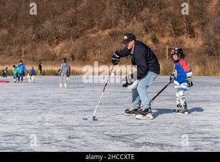 Valganna, Lombardei, Itay - Januari 19,2020: Vater mit Sohn spielt in der Wintersaison Hockey im Torfmoor von Ganna. Regionalpark Campo Dei Fiori i Stockfoto